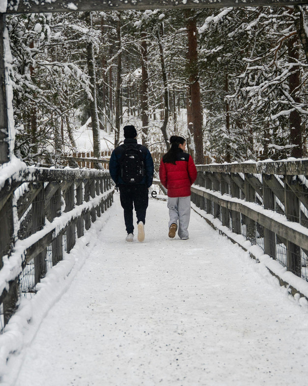 Two people walking down a snowy bridge 