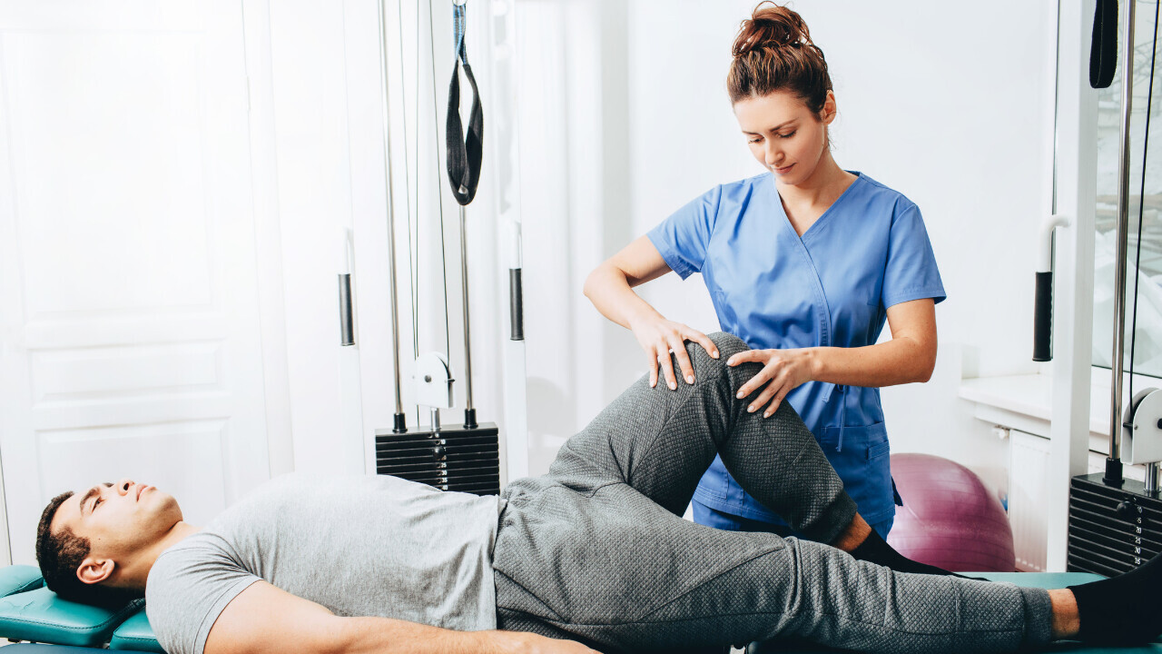 A physiotherapist working on a mans knee after surgery