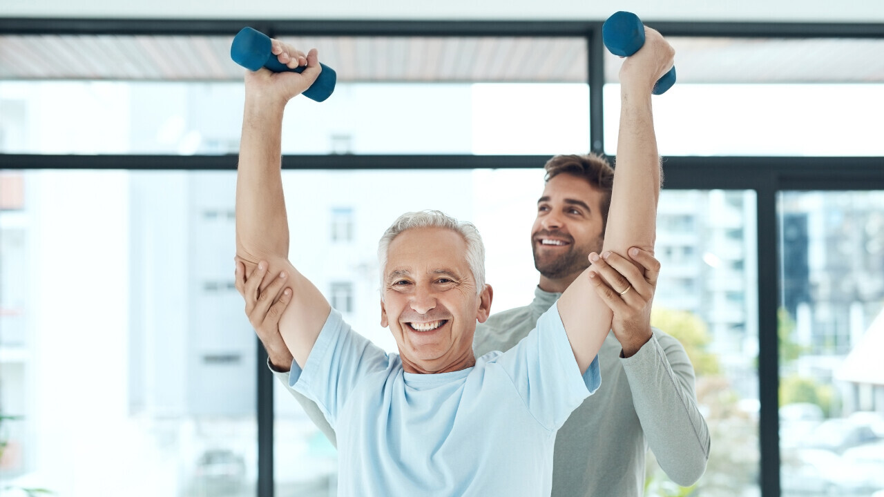A physiotherapist and a patient working on lifting weights. 