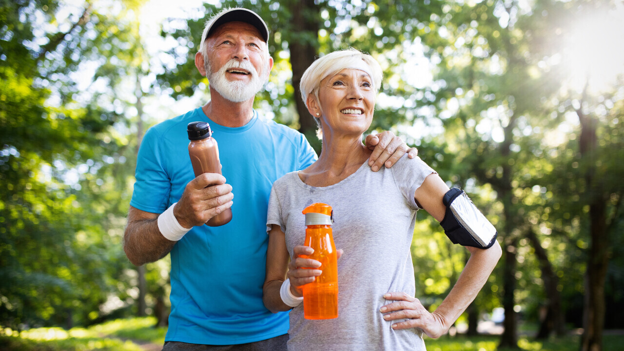 a guy and girl out for walk holding water bottles 