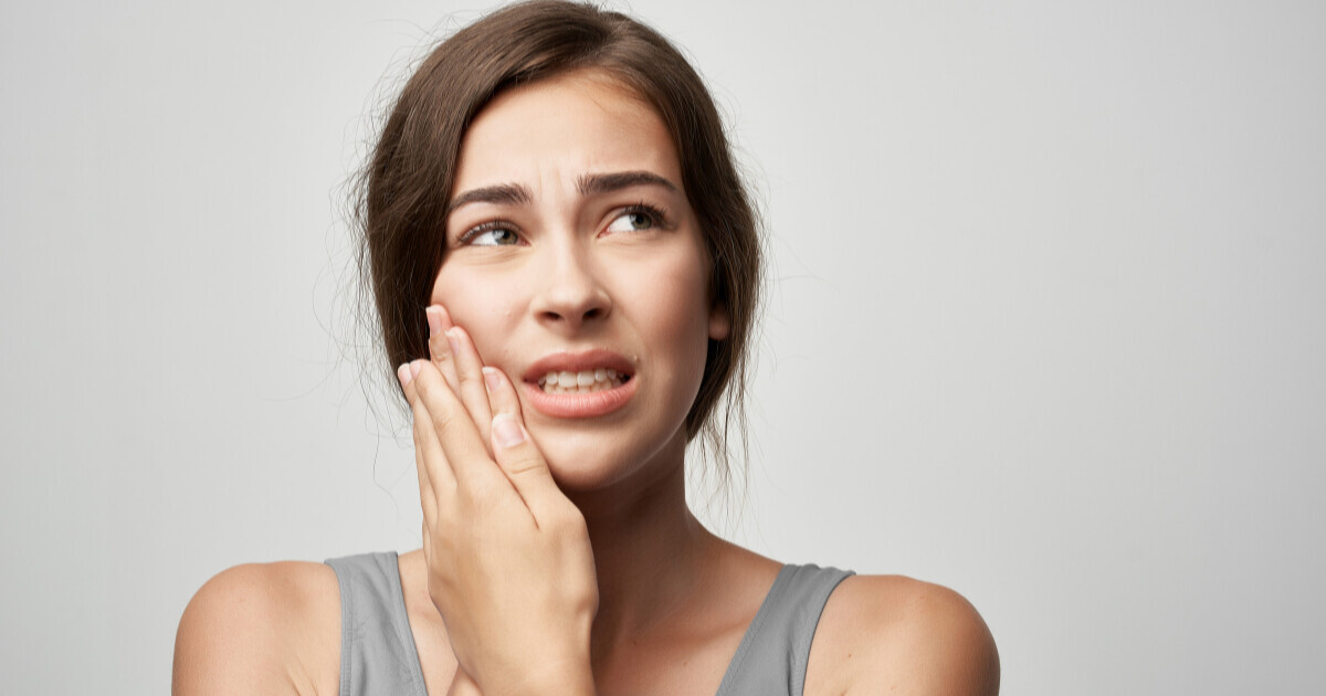 a lady holding her jaw 