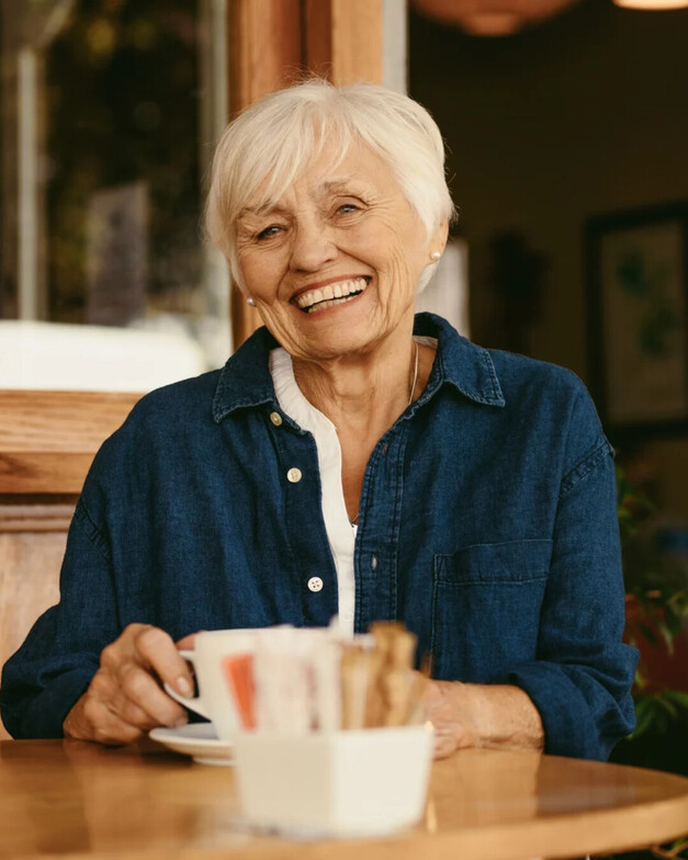 An older lady having a cup of coffee smiling Ottawa